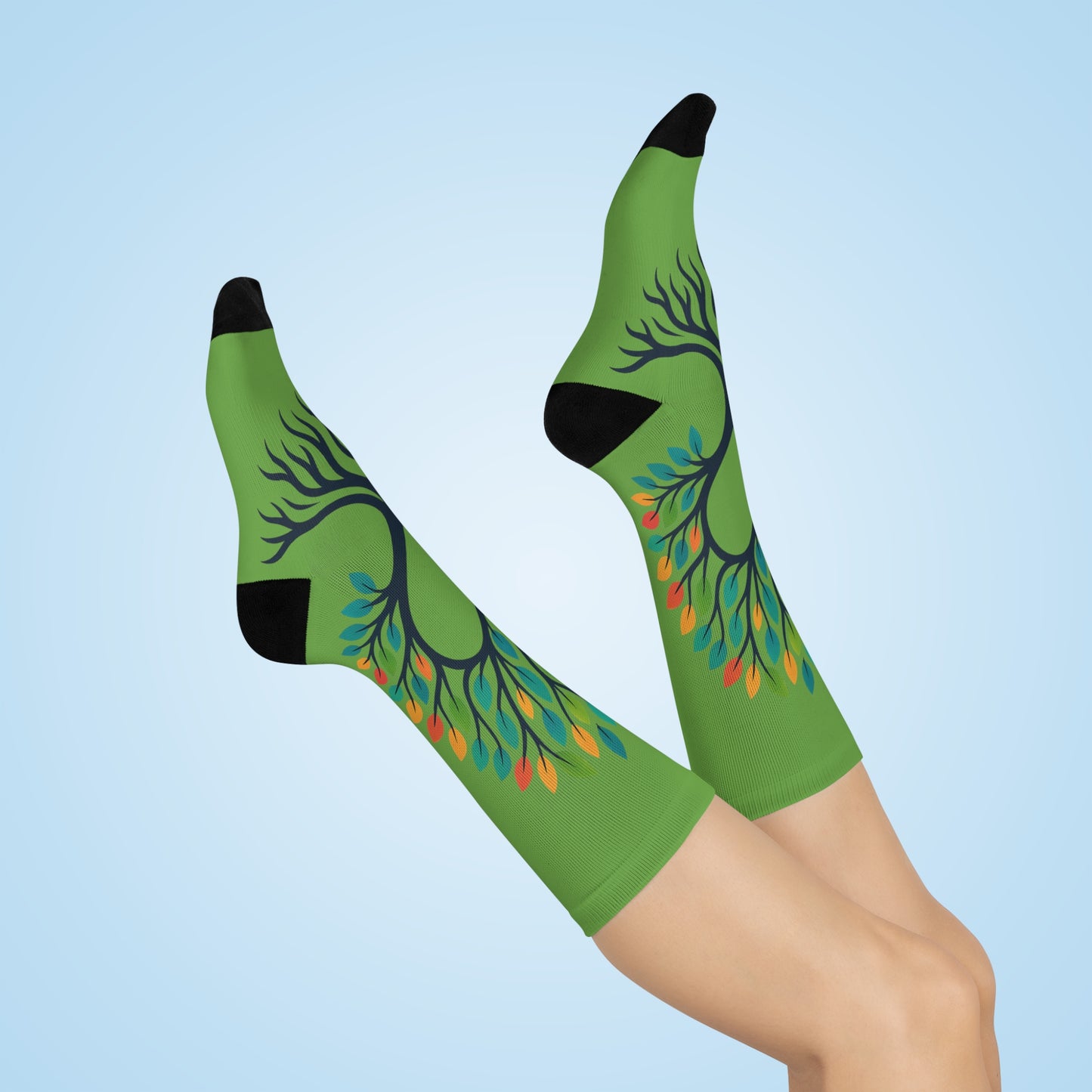 Green knee-high socks with tree design worn by a person on a light blue background