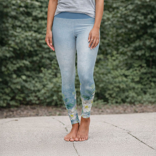 Person wearing light blue leggings with floral pattern standing outdoors.