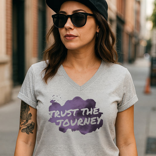 Woman wearing a gray t-shirt with 'Trust The Journey' design on a city street.