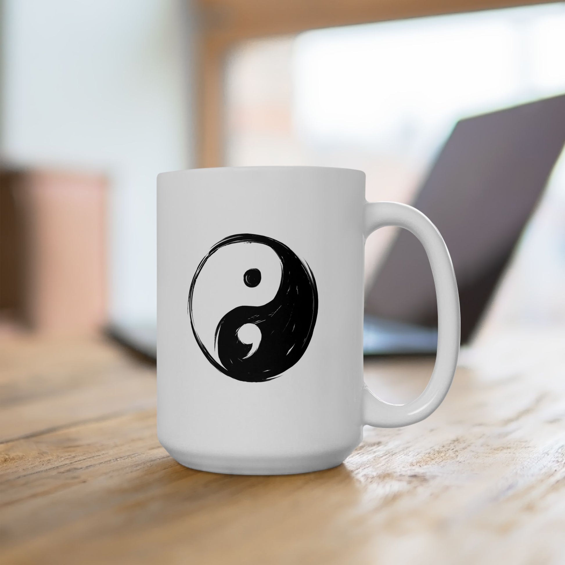 White mug with a black yin yang symbol on a wooden surface