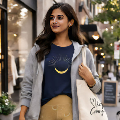 Woman walking on a street wearing a blue shirt with a moon design, gray jacket, and yellow pants.